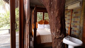 Ein Zimmer mit einem hölzernen Bett, einem weißen Waschbecken und Blick auf Grünfläche.