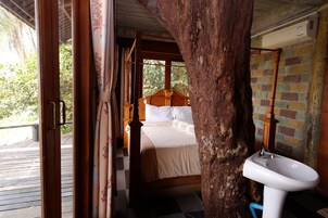 Una habitación con una cama de madera, un lavamanos blanco y vistas a zonas verdes.