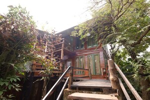 Una escalera de madera que lleva a un edificio rodeado de abundante follaje.