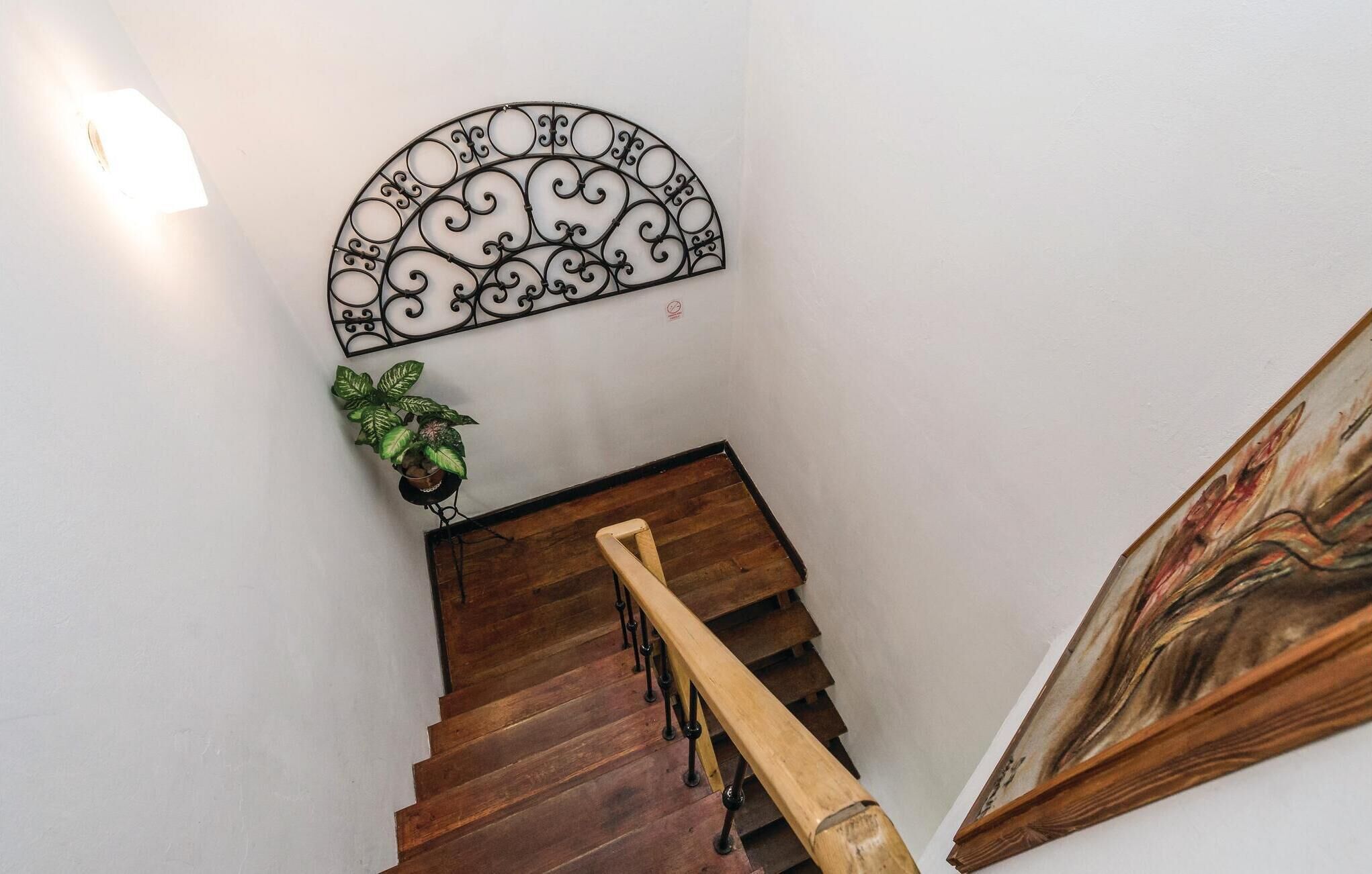 A wooden staircase with a metal railing, a potted plant, and a wall-mounted decorative piece.