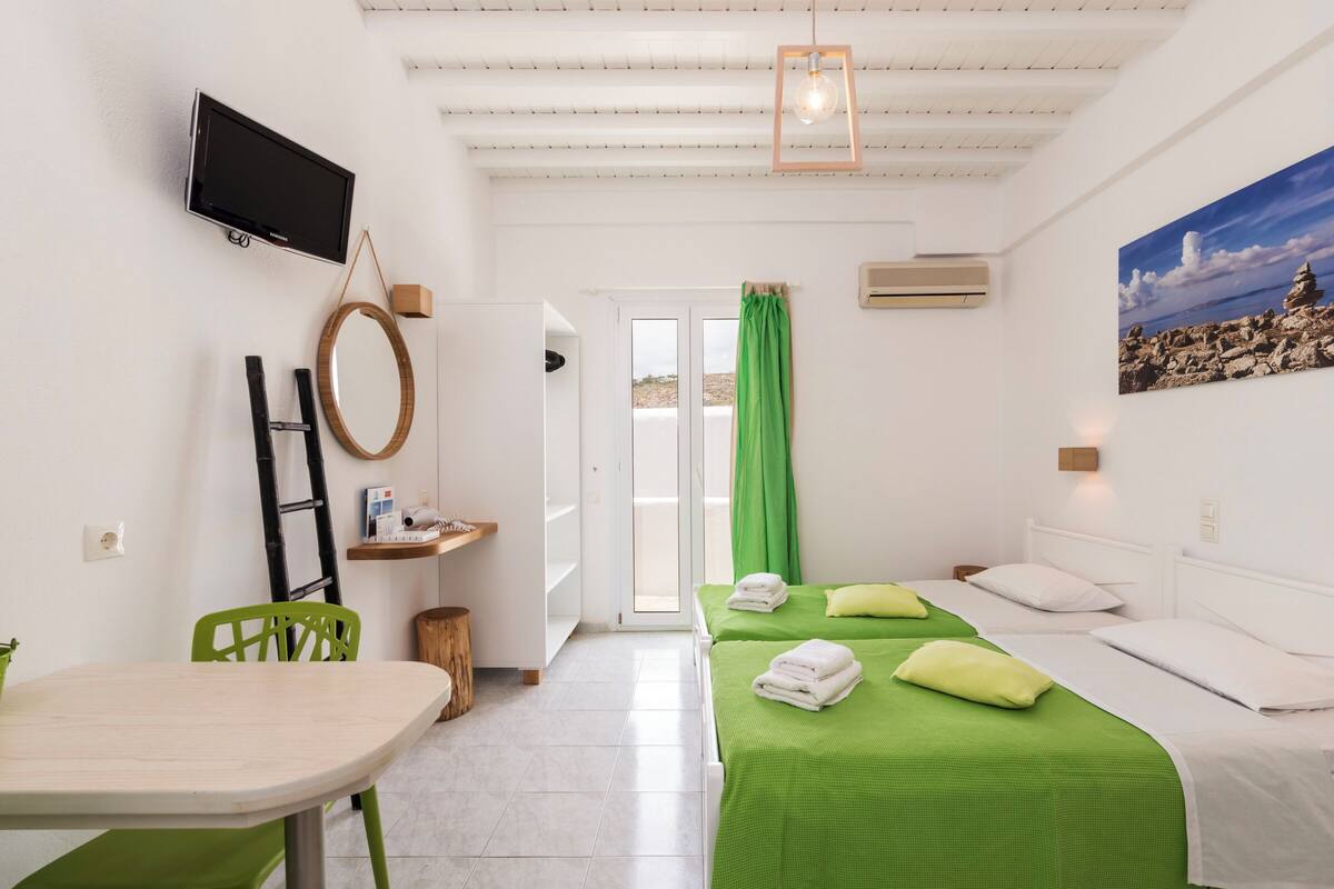 A hotel room with two beds, a TV, a desk, and a chair.