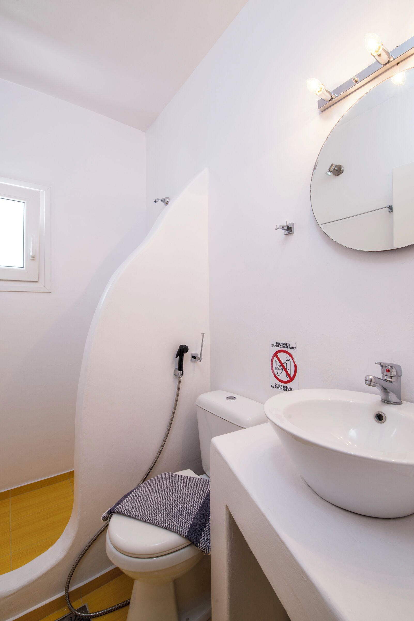 A bathroom with a toilet, sink, and mirror.