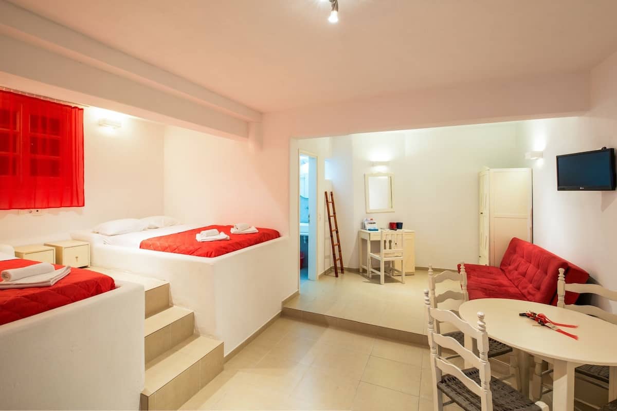 A hotel room with a bed, a chair, a small table, and a TV.