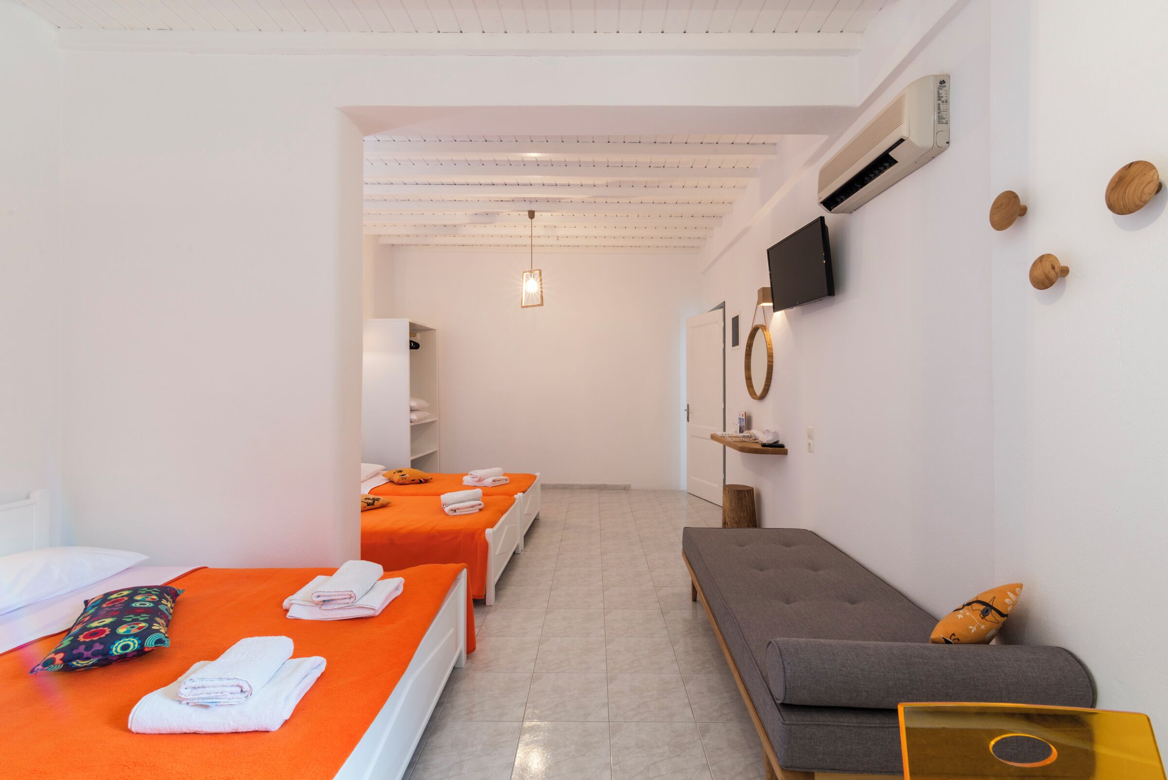 Une chambre d’hôtel avec deux lits, un canapé, une télévision et une petite table.