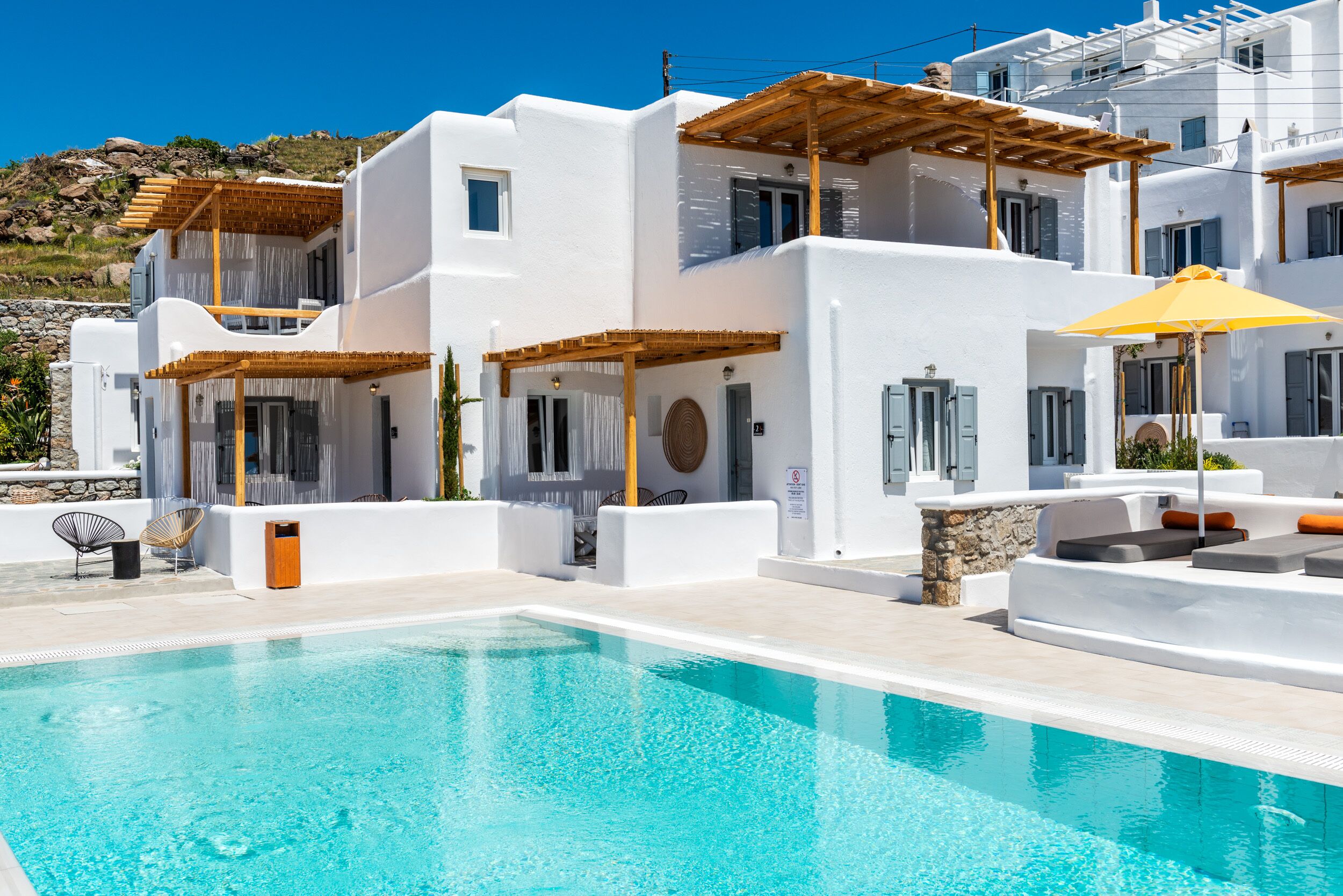 A modern white building with a pool, outdoor seating, and a pergola.