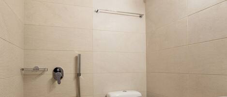 A small, modern bathroom with a shower, toilet, and sink.