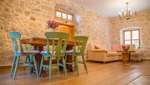 Una habitación rústica con pared de piedra, muebles de madera, una mesa de comedor de madera y un sofá.
