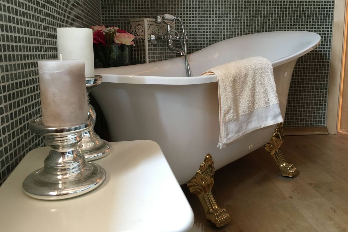 Un baño con una bañera independiente, un lavamanos blanco y un candelabro decorativo.
