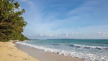 A beach with clear skies, gentle waves, and a sandy shore.