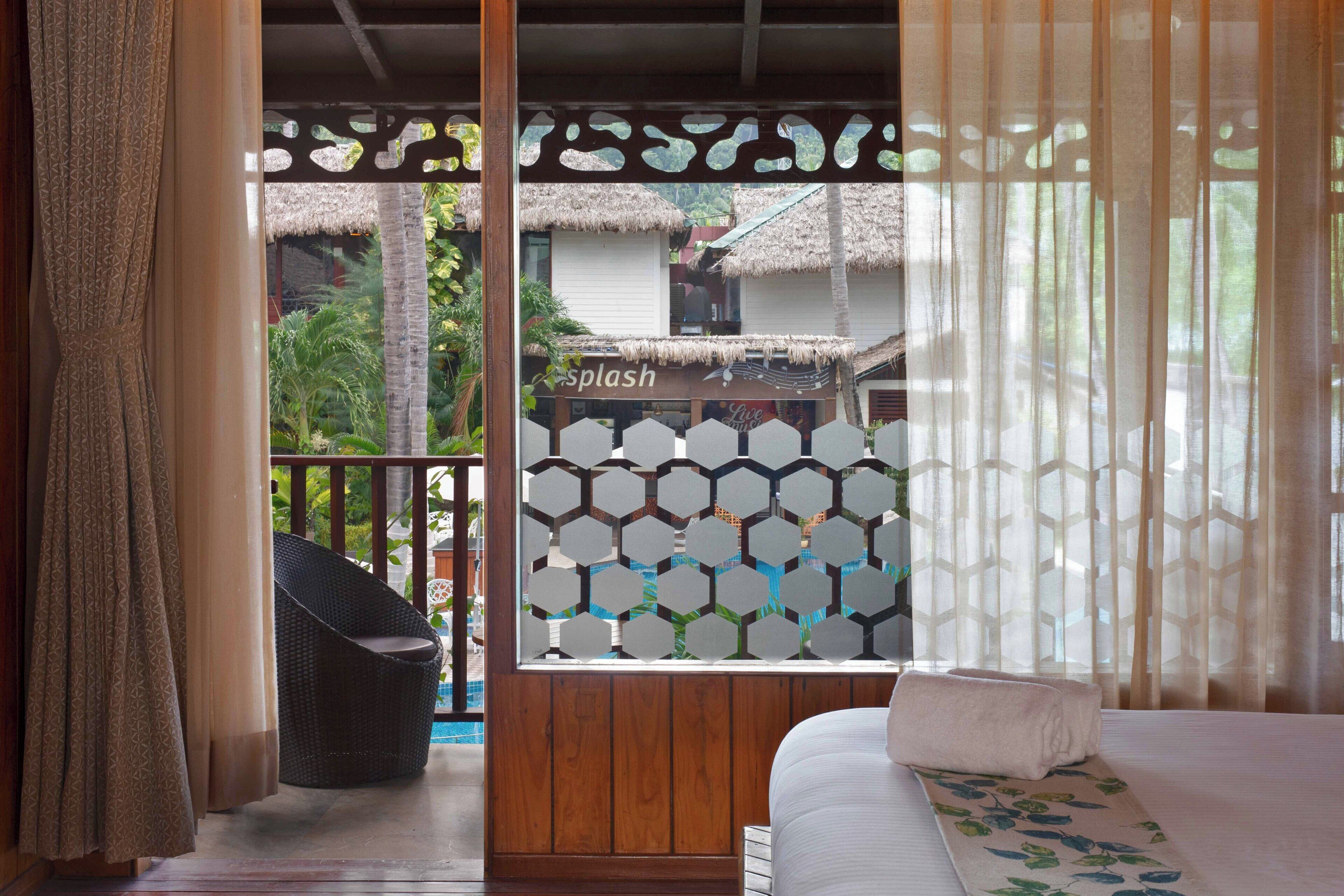 A room with a bed, a wicker chair, and a view of a pool area with a sign reading "Splash".