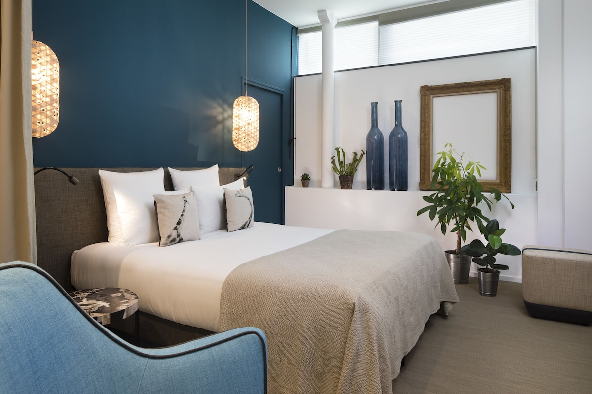 Un dormitorio moderno con una cama grande, dos mesitas de noche, una silla y una planta en maceta.