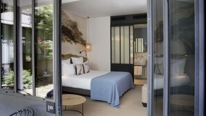 Une chambre d’hôtel moderne, équipée d’un lit, d’une table de chevet et offrant une vue sur l’extérieur.