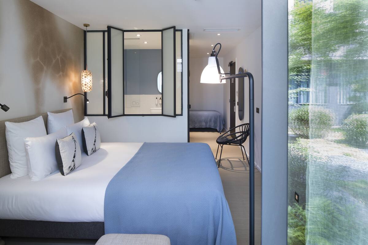 Un dormitorio moderno con una cama grande, una mesita de noche, una silla y un espejo.