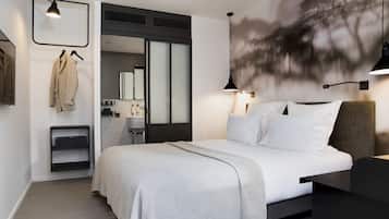 Een moderne hotelkamer met een groot bed, een bureau, een kledingkast en een badkamer, zichtbaar door een geopende deur.
