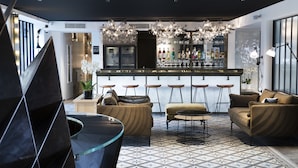 Un espace bar moderne, doté d’un comptoir, de tabourets et d’une variété de bouteilles. L’espace détente comprend des canapés et une table basse.