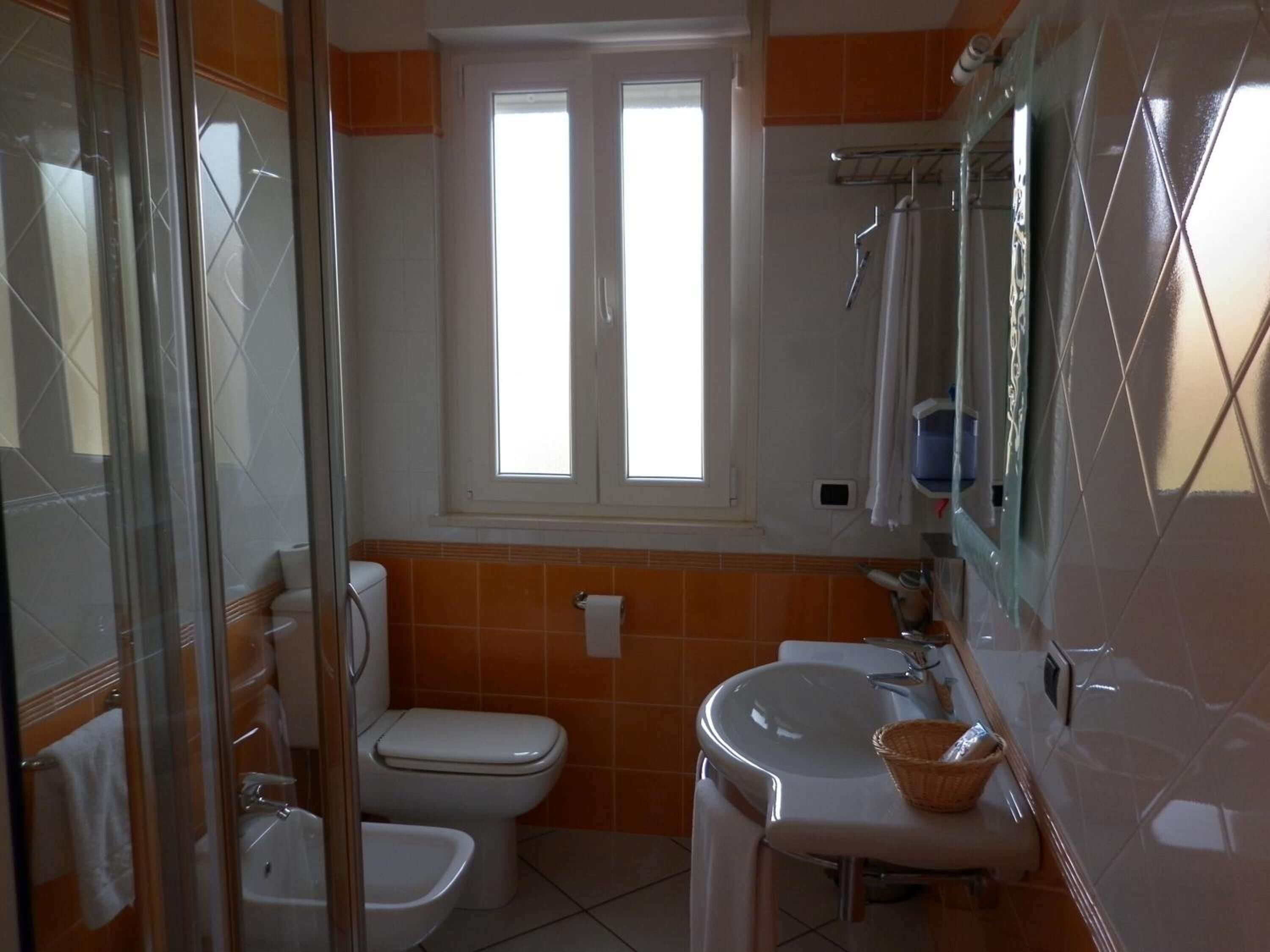 A bathroom with a toilet, sink, and shower area.
