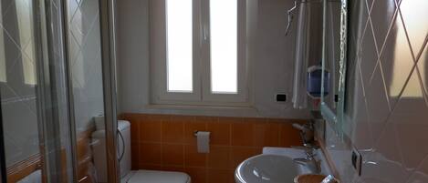 A bathroom with a toilet, sink, and shower area.