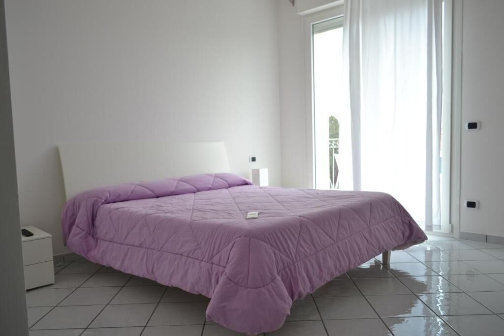 A bedroom with a bed, a nightstand, and a sliding glass door leading to a balcony.