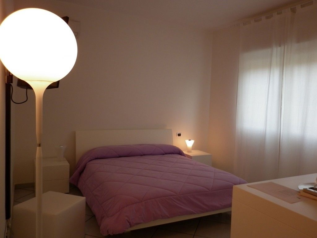 Una camera da letto con un letto, comodini, una lampada e una finestra con tende.
