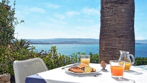 A table with breakfast items and a view of the sea.