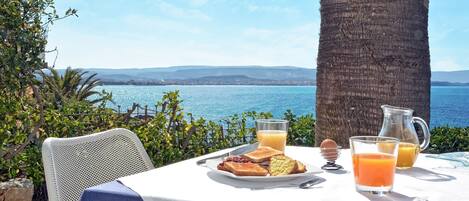 Une table dressée avec des aliments pour le petit-déjeuner et une vue sur la mer.