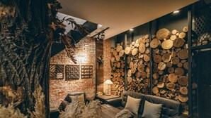 A cozy room with a brick fireplace, a leather sofa, and a wall of stacked logs. - Original Hostel (Chishang)