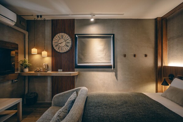 A modern bedroom with a bed, bedside table, and a wall-mounted clock.