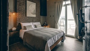 A bedroom with a brick wall, a large bed, a window with curtains, and a view of the outdoors. - Original Hostel (Chishang)