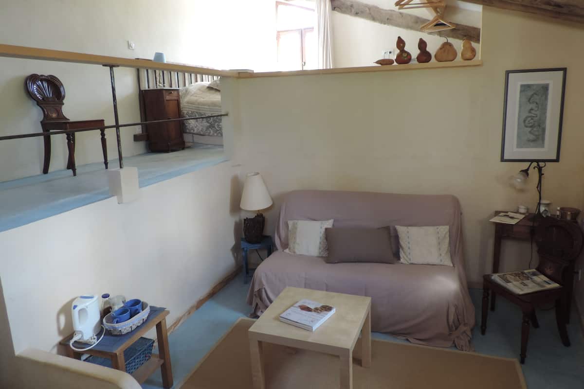 Une pièce confortable avec un canapé, une petite table, une chaise et un banc en bois.