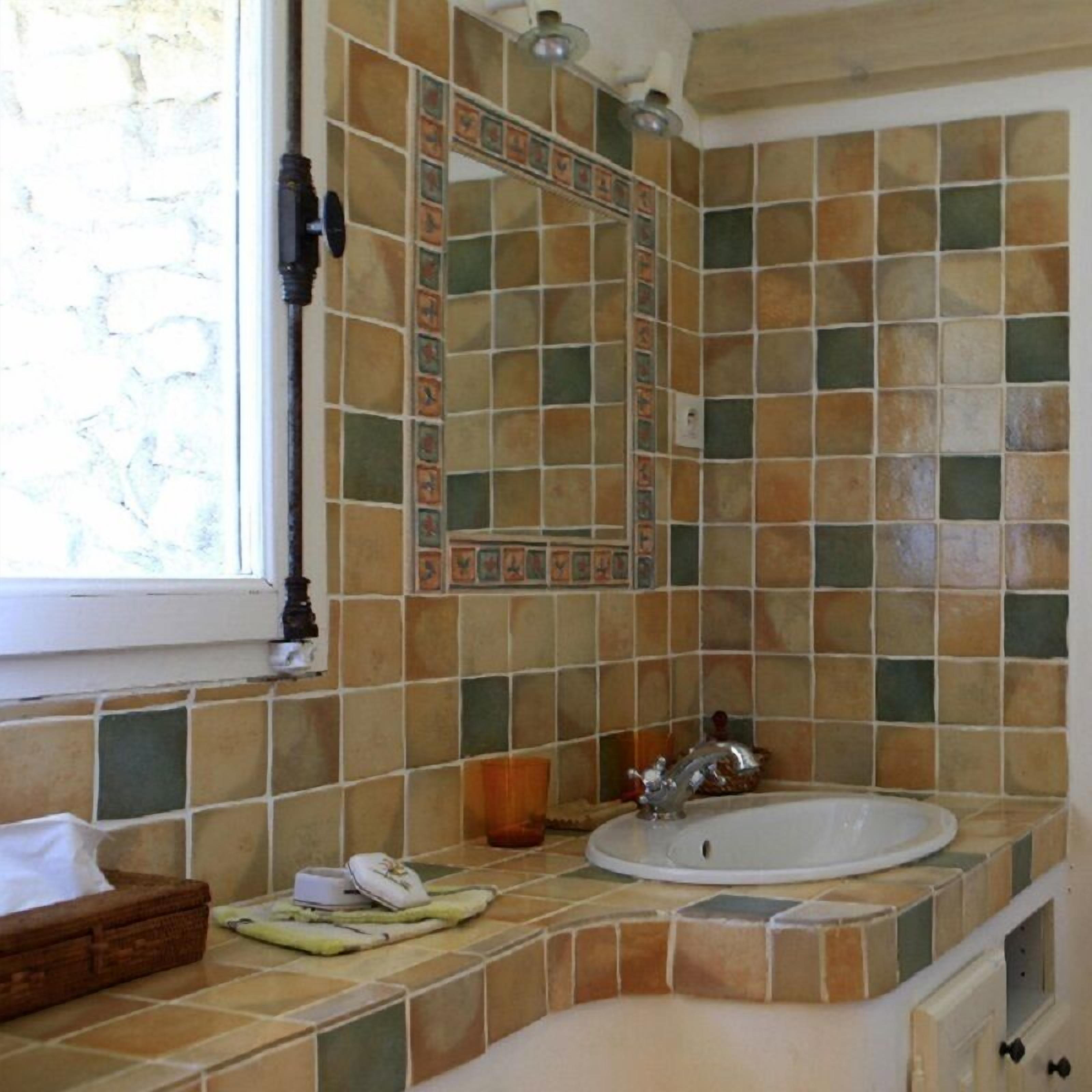 A bathroom with a sink, mirror, and tiled walls.