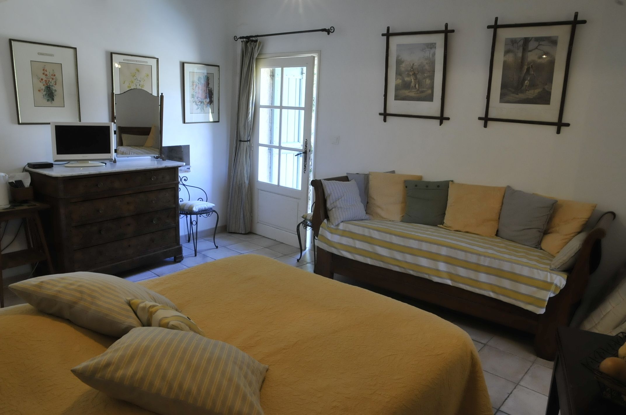 A bedroom with a bed, a dresser, a desk with a computer, and a window with curtains.