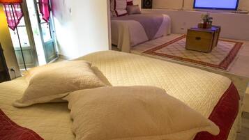 A bedroom with a large bed, a TV, a bedside table, and a window with curtains.