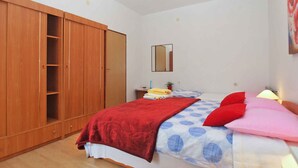 Une chambre à coucher comprenant un lit, une armoire, un miroir et une table de chevet avec une lampe.
