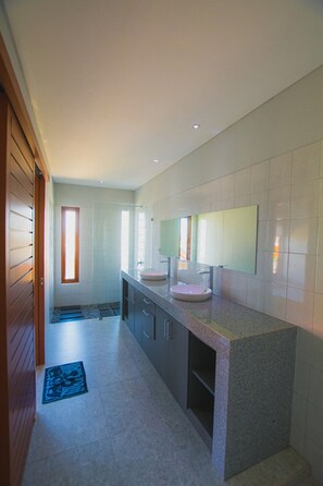 Un baño moderno con un espejo grande, dos lavamanos y una ducha a pie.