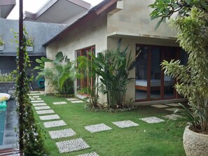 A modern house with a swimming pool, surrounded by lush greenery and a well-maintained lawn.