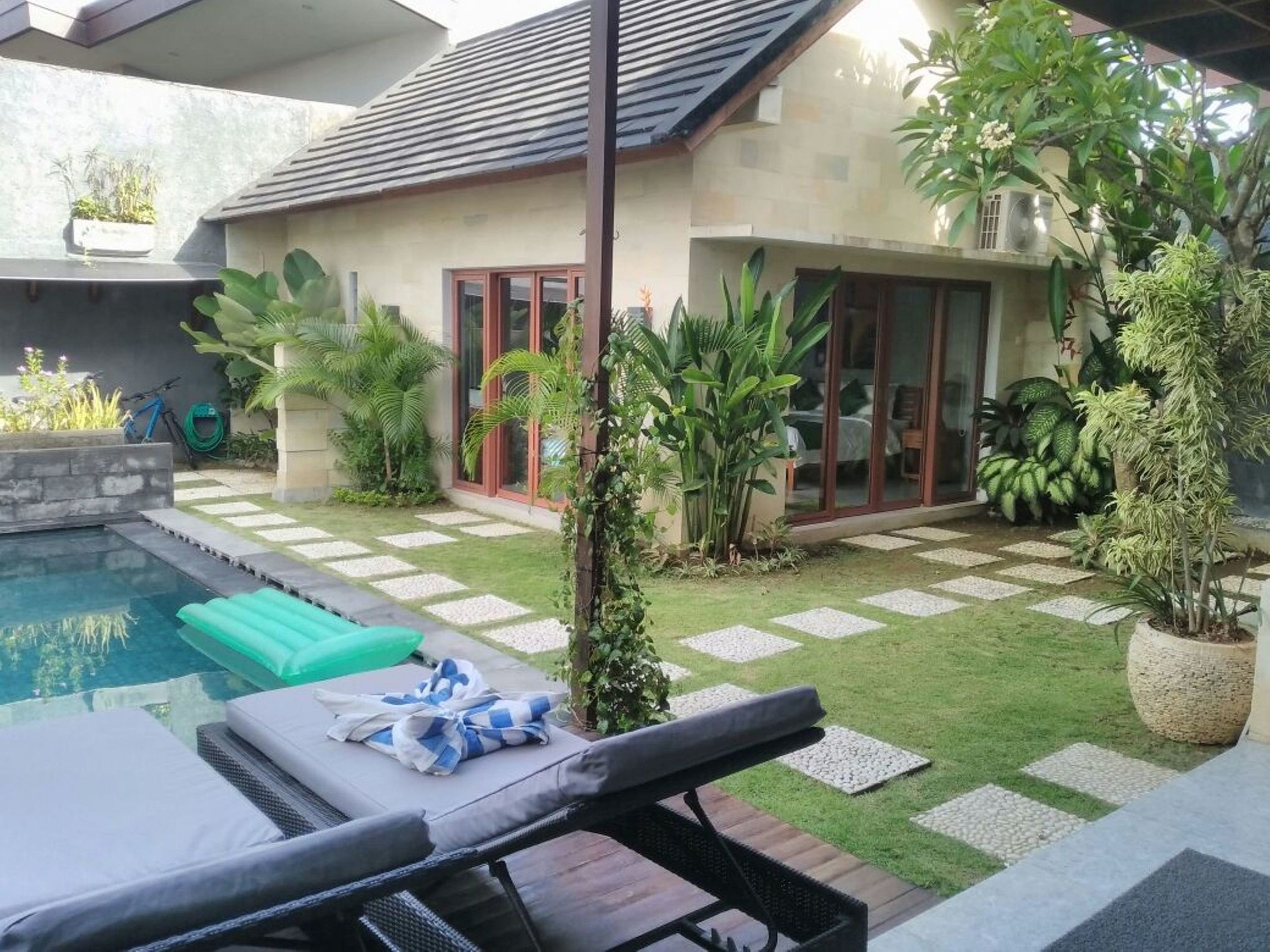 A modern house with a swimming pool, outdoor seating, and lush greenery.