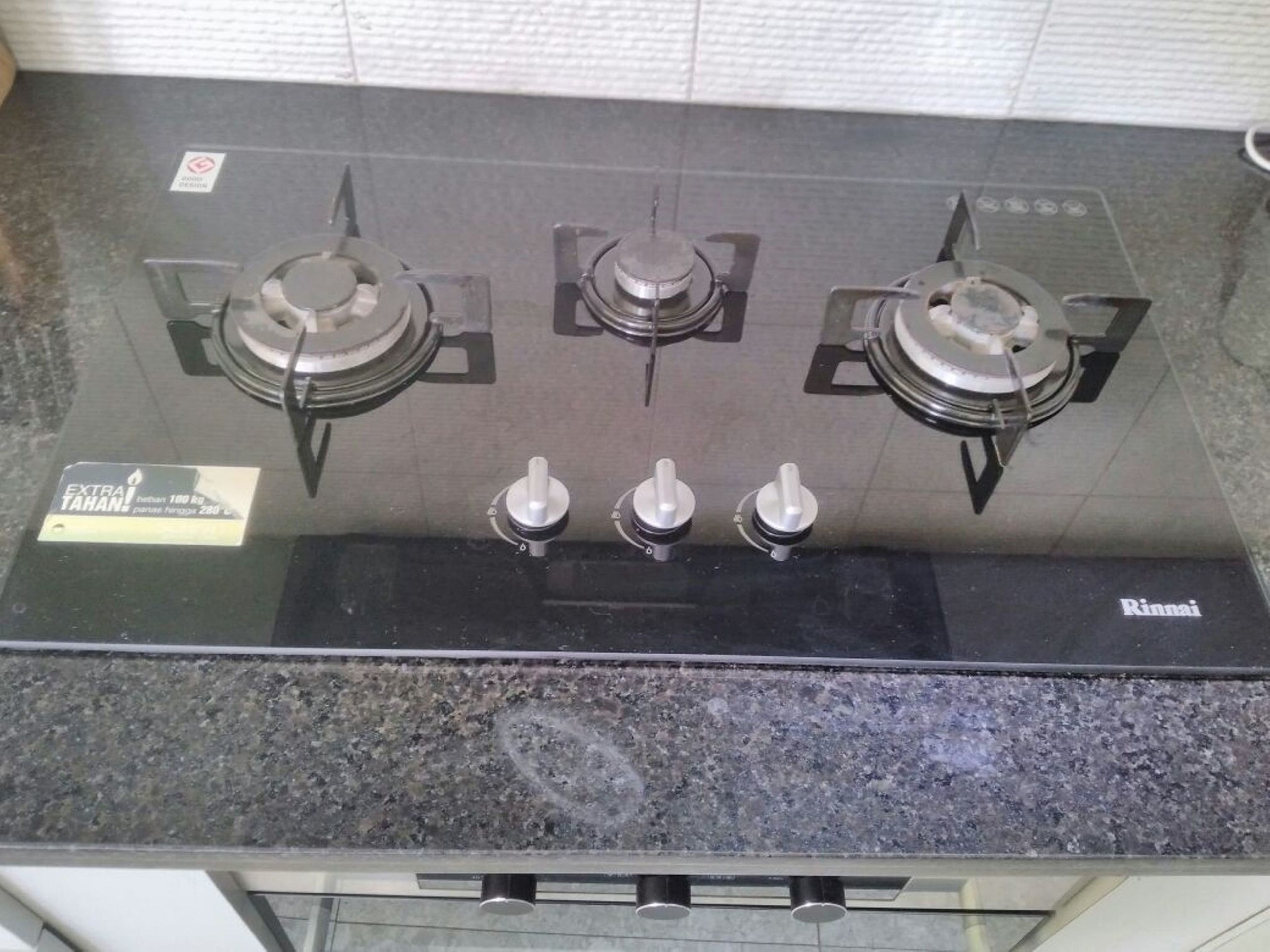 A kitchen with a black countertop and three burners.