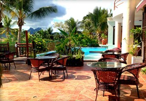 A poolside area with wicker furniture and a view of mountains. - Le Gite du Bonheur (Tamarin)
