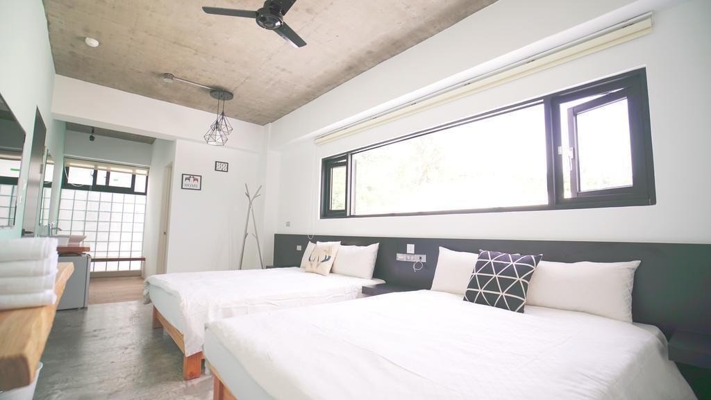 A hotel room with two beds, a ceiling fan, a window with blinds, and a view of the outdoors.