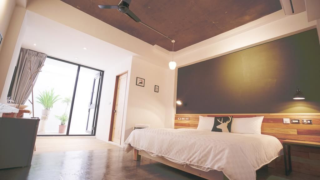 A modern hotel room with a large bed, a desk, a chair, and a view of the outdoors.