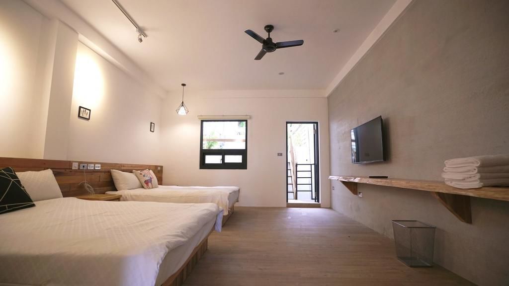A hotel room with two beds, a ceiling fan, a TV, and a window.