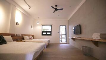 A hotel room with two beds, a ceiling fan, a TV, and a window.