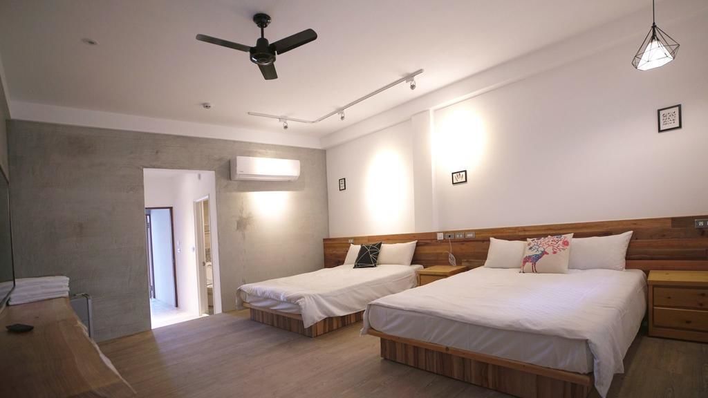 A hotel room with two single beds, a ceiling fan, and a wooden headboard.