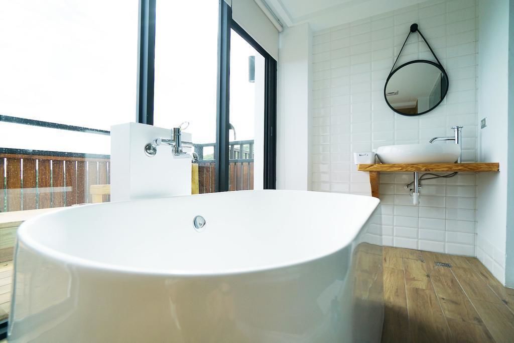 Un baño moderno con una bañera independiente, un tocador de madera y un espejo grande.