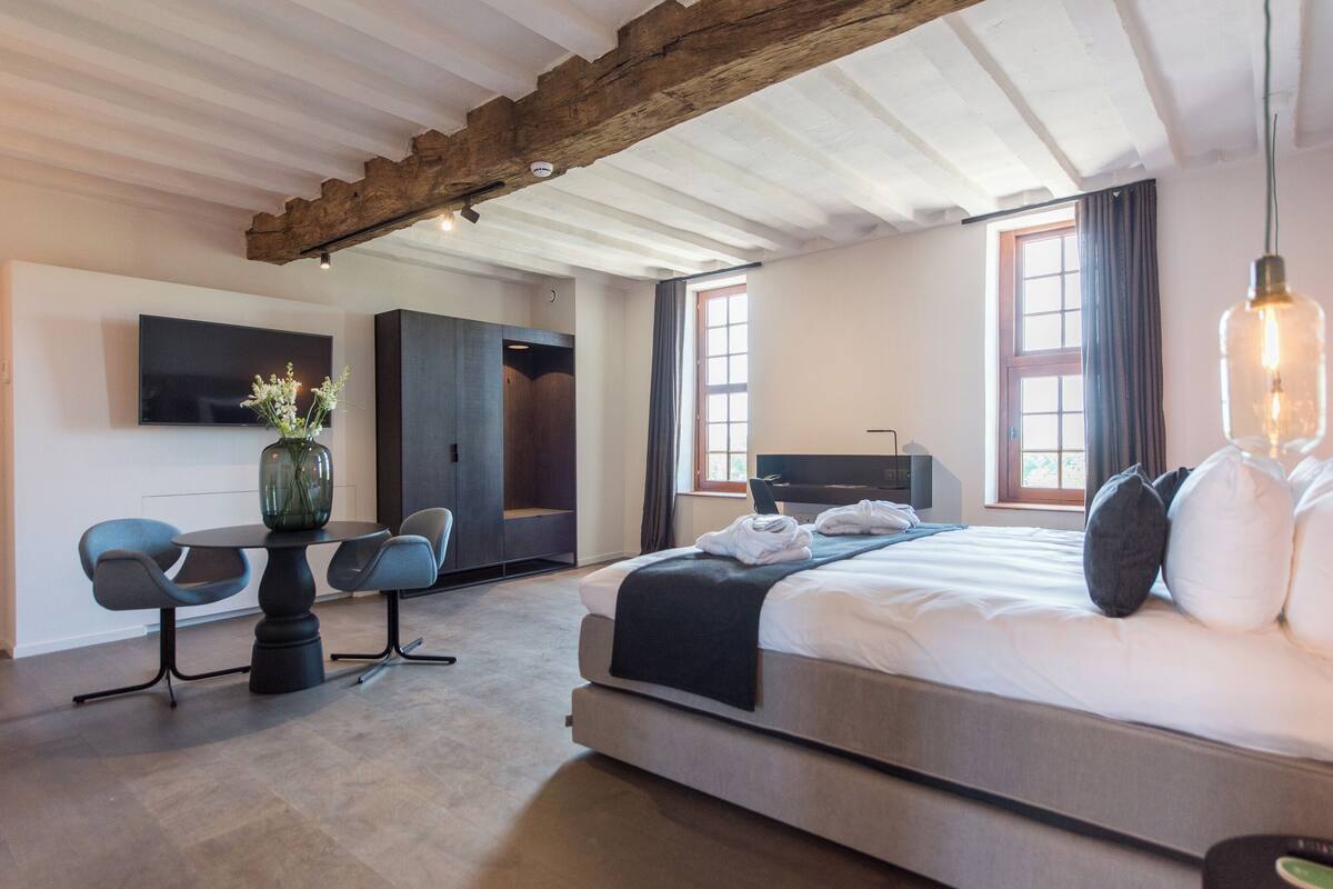 Une chambre d’hôtel moderne équipée d’un grand lit, d’un bureau avec des chaises, d’une télévision et d’une armoire.