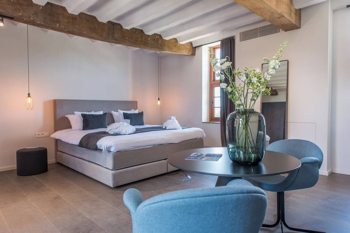 Une chambre d’hôtel moderne avec un lit, une table de chevet et un vase de fleurs.