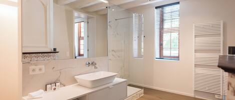 A modern bathroom with a large mirror, a white sink, and a glass shower enclosure.