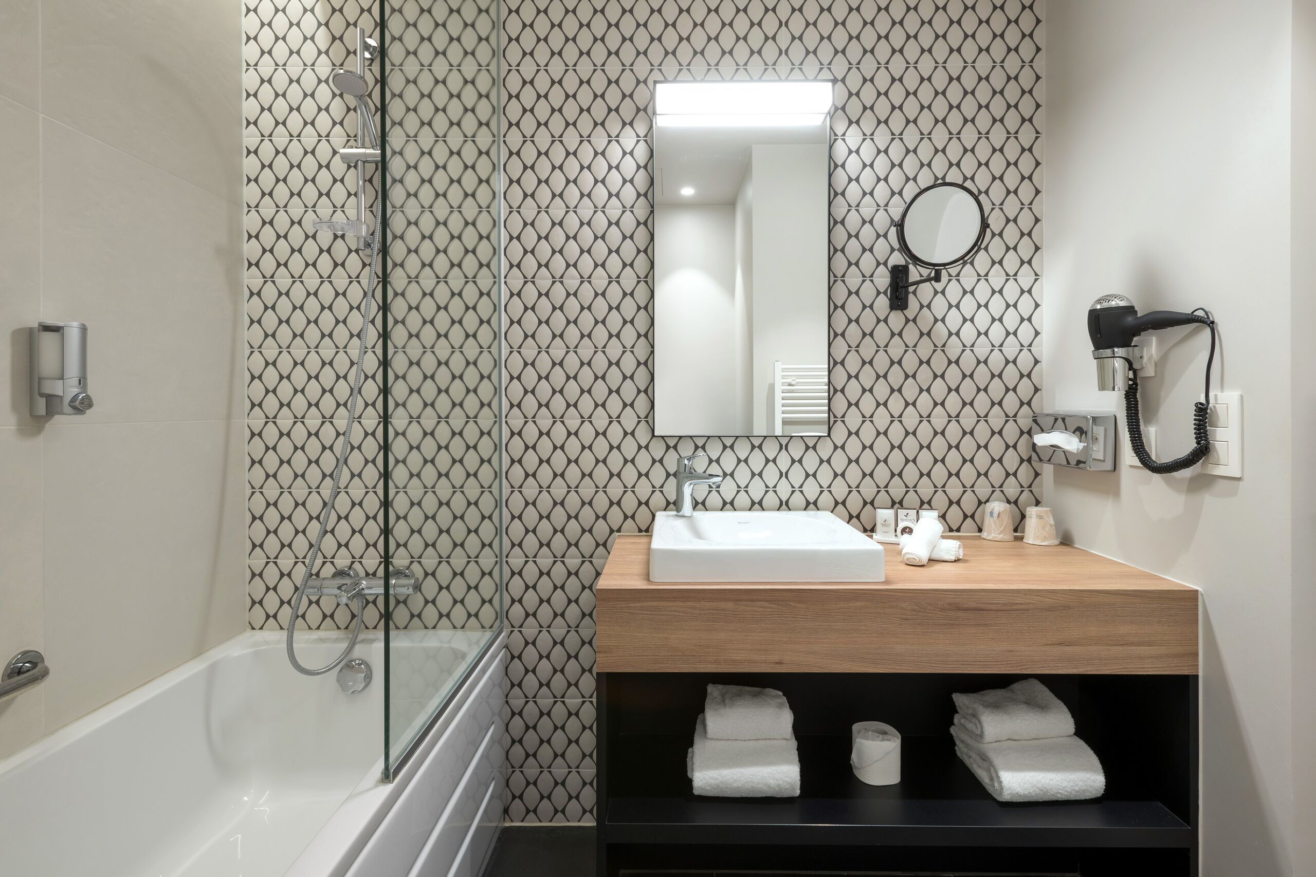 A modern bathroom with a glass-enclosed shower, a wooden vanity with a sink, and a mirror above it.