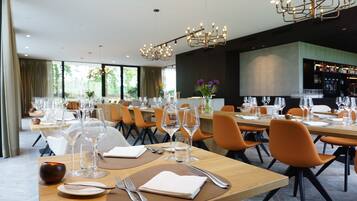 A restaurant with multiple dining tables, each set with plates, cutlery, and wine glasses.