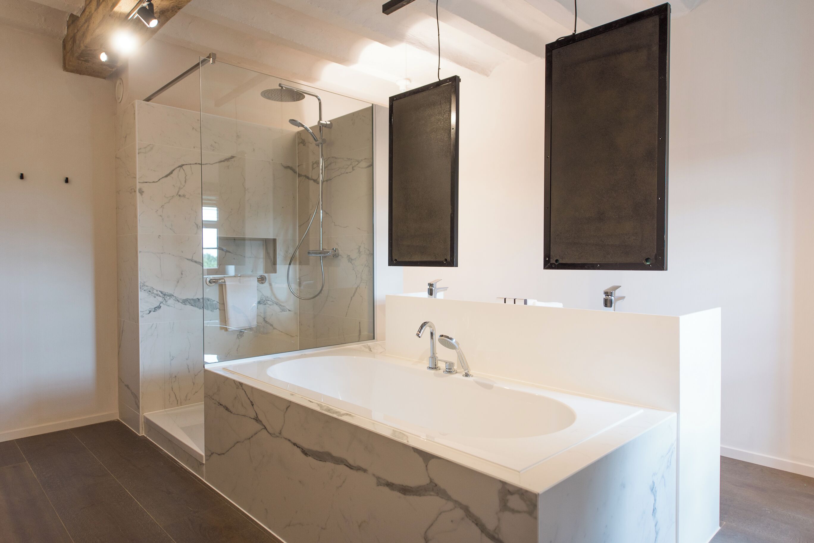 A modern bathroom with a large marble sink, a glass-enclosed shower, and two wall-mounted mirrors.